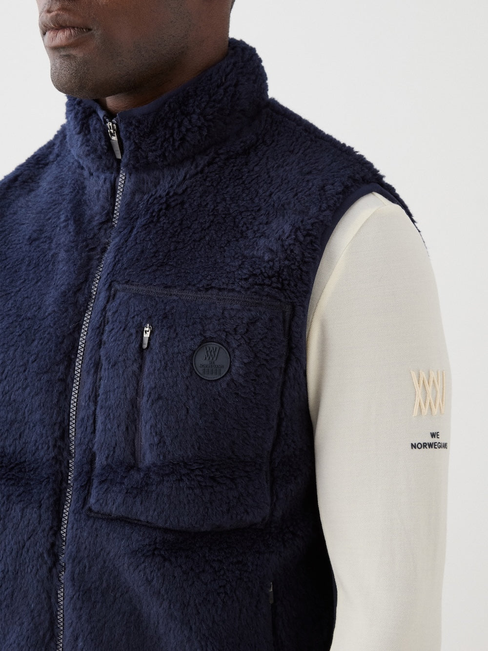 We Norwegians | FW25 | Mens Kebnekaise Vest_Navy blue | Model wearing this fleece vest with front zipper opening, zipped chest pocket and side pockets -over an off-white top | Shot against an off-white background | Close-up