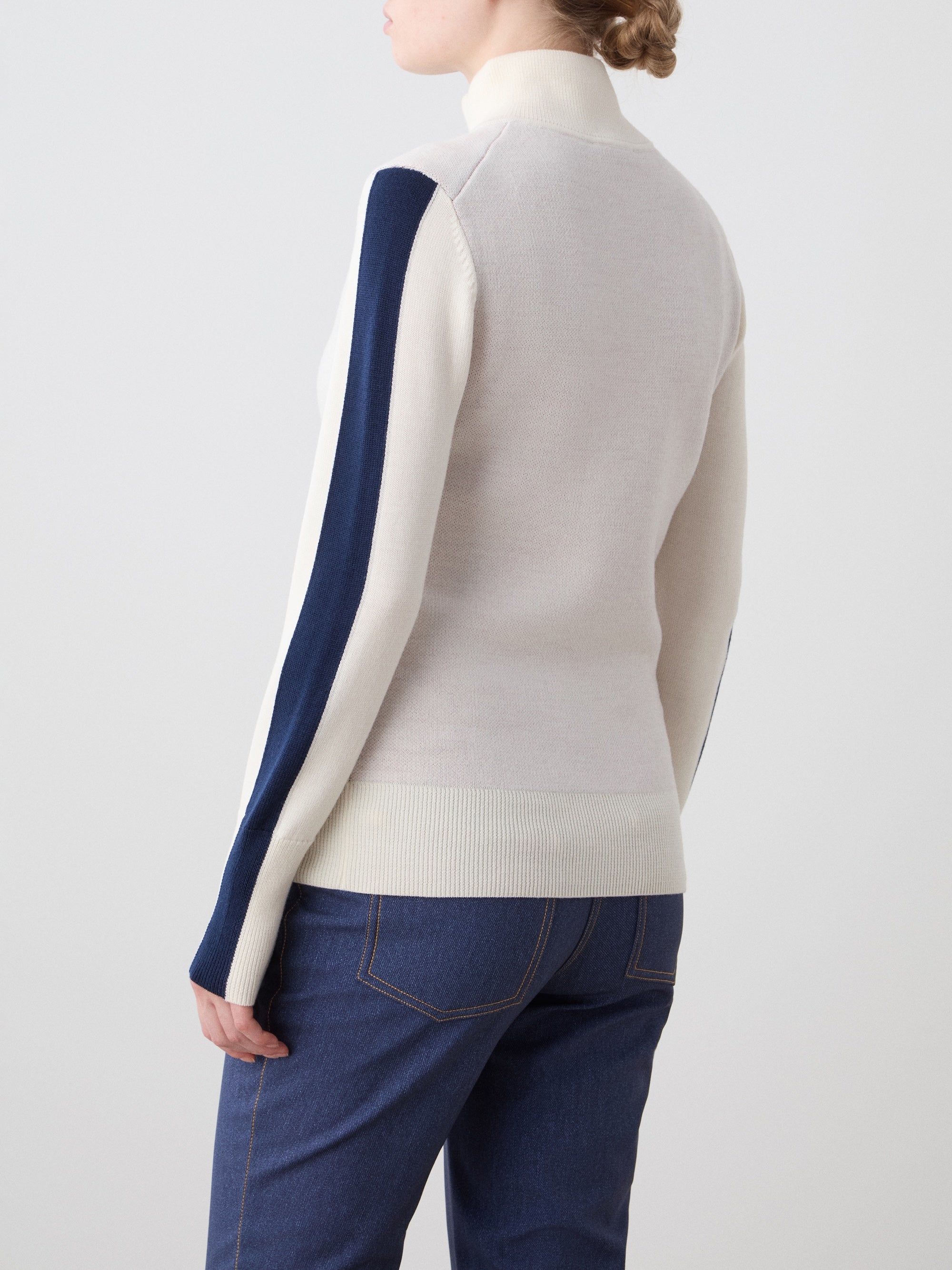We Norwegians | FW25 | The model is wearing womens Afterski zip-up in cream which has the logo and 1/4th zipper in the front, against an off white background | Back view