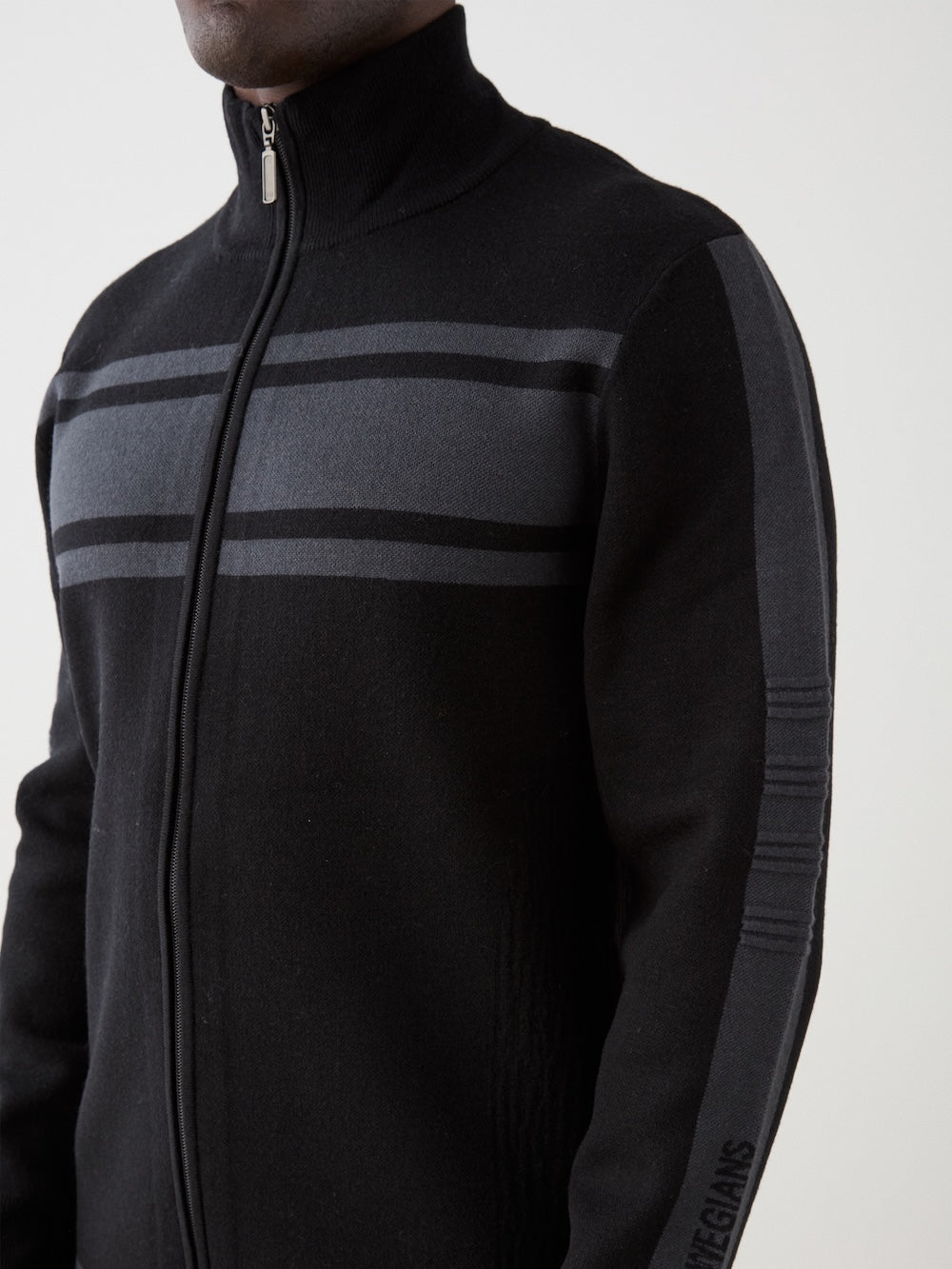We Norwegians | FW25 | Mens Rocky Full ZipUp_Black | Model wearing this fine knitted sweater with a 2-way front zipper opening, designed in a retro style with subtle color blocks on the chest and sleeves | Shot against an off-white background | Close-up